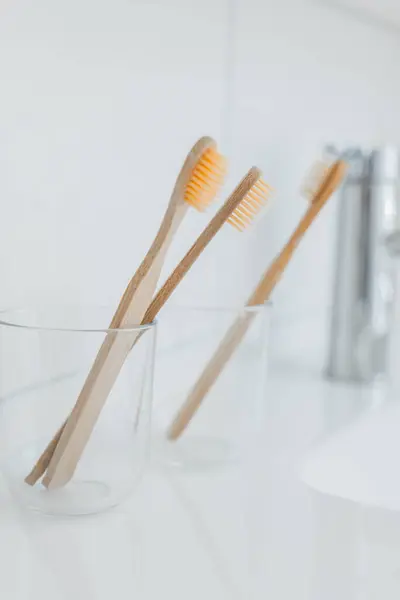 Teeth cleaning. bamboo Toothbrush in bathroom. toothbrush in a transparent glass cup on the sink in a bright bathroom.Human hygiene concept