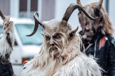 Bulanık sokaktaki Krampus iblisi. Almanya 'daki karnaval geçitleri. Karnaval kostümleri ve karakterleri. Avrupa sokaklarında kış kostüm gösterileri. Krampus canavarının şeytan yüzü.