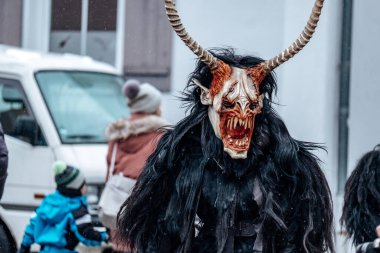 Krampus sokak arka planında. Karnaval kostümleri ve karakterleri. Avrupa sokaklarında kış kostüm gösterileri. Krampus canavarının şeytan yüzü. Geleneksel kültür folklor festivali 