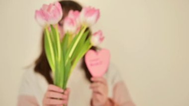 Anneler Günü. Kızı annesine bir buket pembe lale ve pembe bir kalp vermiş. 4k görüntü