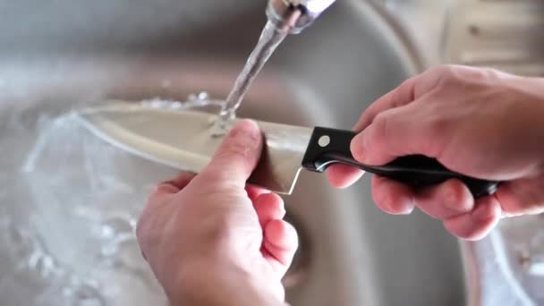 手はナイフを洗っている 犯罪的概念 男は金属のシンクで水を流す下で大きなナイフを洗います 犯罪と殺人シンボル 4Kの映像 — ストック動画