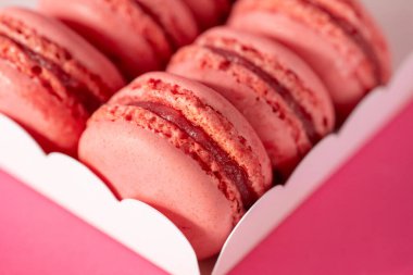 Makarna seti. Pembe arka planda beyaz bir karton kutuda pembe makaronlar. Tatlılar ve tatlılar. Fransız hamur işleri. 