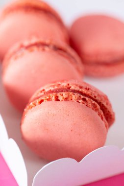 Pembe arka planda karton bir kutuda pembe makaronlar. Tatlılar ve tatlılar. Fransız hamur işleri hazır. Çeşit çeşit tatlı hamur işleri. 