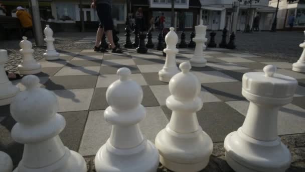 街头象棋 街头游戏和户外娱乐活动 爸爸和女儿下棋 人们在街上的棋盘上玩着大棋子 心理游戏 4K镜头 — 图库视频影像