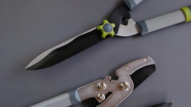 Gri arka planda çelik bahçe aletleri. Secateurs, loppers ve çim biçme makineleri. 4k görüntü