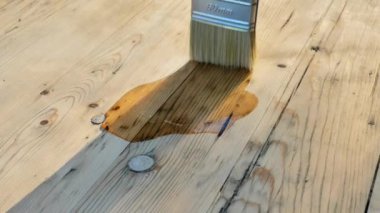 Odun için yağ. Fırça, ahşap bir masaya yağ sürer. Tahta tahtaların yağ ile döllenmesi, ahşabın çevresel faktörlere karşı dayanıklılığını ve direncini arttırmak için kullanılan bir süreçtir. 4k görüntü