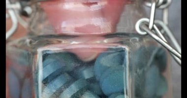 Zeytinyağı tabletleri. Parmaklar cam bir kavanozdan spirulina kapsülleri alır. Zülkül insan emilimi. Yeşil kuru spirulina tabletleri. Tabletlerdeki algler. Doğal iyot kaynağı. Süper yemek. .