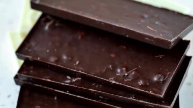 Siyah ve beyaz çikolatalar. Beyaz mermer bir arka planda dönüyor. Tatlılar ve tatlılar. Beslenmedeki çikolatanın faydaları ve zararları. 4k görüntü