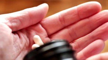 Vitaminler bir kavanozdan avucunuza dökülür, yakın plan. İnsan beslenmesinde takviye ve vitamin. 4k görüntü