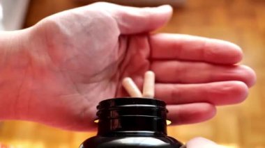 İlaçlar ve vitaminler. Kadın eline beslenme takviyesi kapsülleri döküyor. İnsan diyetinde beslenme takviyeleri almak için norm. 4k görüntü