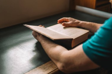 Ellerinizdeki kitabı açın. Ahşap bir masada kitap okuyan bir adam. Kütüphanede kitap sayfalarını karıştıran bir erkek. Edebiyat ve okuma kavramı.. 