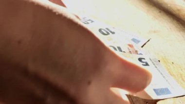 Avro banknotlarını masaya dizen eller. Tahta bir masanın üzerinde nakit euro banknotları. Avro banknotları ellerinde. Para sayımı. 4k görüntü