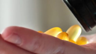 Omega asit jelatin kapsülleri bir kavanozdan avuç içine dökülür. Kadın ellerinde balık yağı kapsülleri. Sağlıklı yağlar. Beslenme takviyeleri ve vitaminler. 4k görüntü