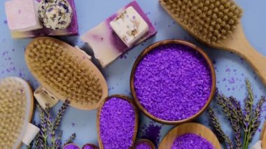 Yuvarlak kaselerde deniz lavantası tuzu, banyo sabunu, doğal kıllı fırçalar ve lavanta çiçekleri mor bir arka planda düzenlenir. Lavanta özlü kozmetik spa seti. 4k görüntü
