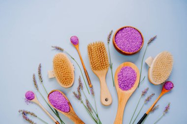 Mor bir arka planda lavanta ezilmiş kozmetik seti. Lavanta tuzu ve doğal kıllı fırçalar ve lavanta çiçekleri. Lavanta organik vücut kozmetikleri..