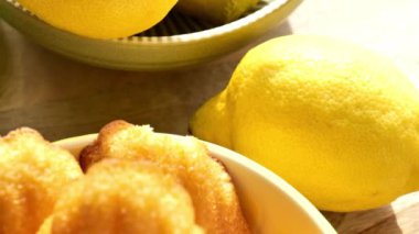 Sarı seramik kasede limonlu bisküvi. Tatlı Fransız tatlısı. Limonlu Fransız kurabiyeleri ve limonlu meyveler. Güneş ışığı yakın çekim. Fransız kurabiyeleri. 4K görüntü.
