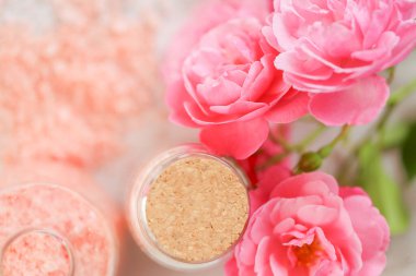 aromatik tuz. Cam kavanozlarda spa banyosu tuzları ve köhne beyaz arka planda gül çiçekleri. Gül özü ve güzel kokulu gül tuzu. Aromaterapi ve kozmetik. Organik kozmetik tuz.
