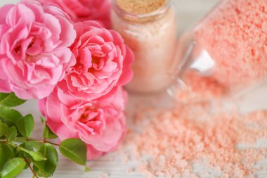 aromatik pembe tuz. Gül özlü kozmetik ürünü. Cam kavanozlarda spa banyosu tuzu ve eski püskü beyaz arka planda pembe güller. Gül özü ve güzel kokulu gül tuzu. Aromaterapi