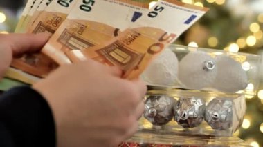 Noel tatilleri için harcamalar. Parlayan Bokeh çelenkleri için Avro banknotları sayan eller. 4k görüntü