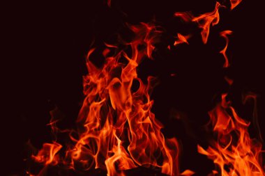 Karanlıkta alevler ve kıvılcımlar. Alevli arka plan. Kırmızı siyah kıvılcımlar ve alevler. Siyah arka planda ateş dokusu. Ateşli duvar kağıdı. Yakın çekim.. 