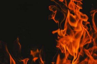 Alevli arka plan. Kırmızı siyah kıvılcımlar ve alevler. Ateşli duvar kağıtları. Siyah bir arka planda alevler.