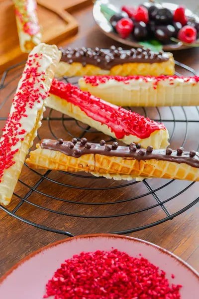 stock image Wafer rolls with dried raspberries and chocolate.Summer Berry Baking. Crispy wafer tube with edible decorations. Crispy sweet dessert. Wafer pastries on the table. Top view 