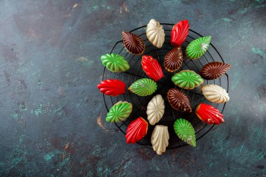 Koyu arkaplanda yuvarlak pasta ızgarasına yerleştirilmiş jöleli kurabiyeler. Üst Manzara. Böğürtlen, çikolata, nane ve kremalı kurabiyeler siyah bir fırında.