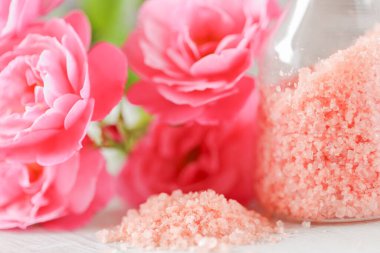  Cam kavanozlarda banyo tuzu ve pejmürde beyaz arka planda pembe güller. Aromaterapi ve kozmetik ürünleri. Gül çiçekleri ve pembe kozmetik tuzları. Organik kozmetik tuz. 