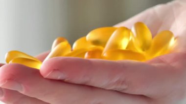 Omega asit kapsülleri. Çoğu zaman kadın ellerinde balık yağının jelatin kapsülleri. Kadın eliyle balık yağı kapsülleri. 4K görüntü.