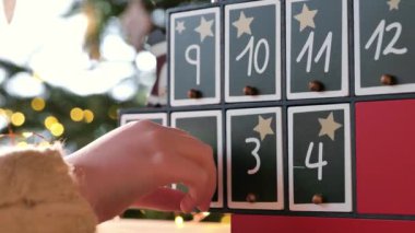 Noel takvimi. Çocuk, Noel ağacı arka planında takvim kapılarını açıyor. 4k görüntü