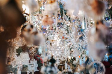 Noel pazarları, panayırdaki bir Noel çadırında gümüş ve beyaz süslemeler, Noel hediyeleri ve tatil süslemeleri. Şölen süslemeleri ve insanlar. Kış tatili atmosferi..