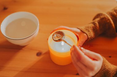 Fortune telling with melting tin.Fun tin casting set for New Years party. woman melts tin over a candle flame on a wooden table clipart