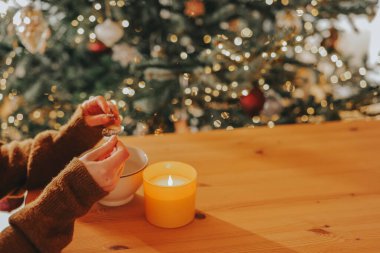 Fortune telling with melting tin.Winter Holiday Traditions.woman examines a piece of molten tin in her hands.New Years Traditions in Germany clipart