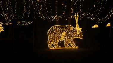 Noel sokak dekorasyonları. Noel Işığı Kurulumları. Karanlıktaki çelenklerden yapılmış geyik ve ayının parıldayan figürleri. Noel tatili duvar kağıdı. 4k görüntü