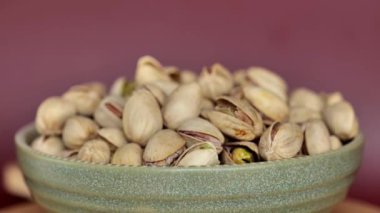 Bir fincan şam fıstığı, bordo bir arka planda dönüyor. Sağlıklı yağ. Sağlıklı bitkisel beslenme. 4k görüntü