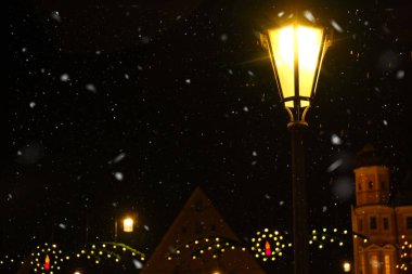 Noel duvar kâğıdı. Parlak fenerler, Noel süslemeleri ve karanlıkta düşen kar. Kış masalı atmosferi. Avrupa 'da Noel tatili. 