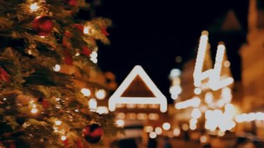 Noel duvar kâğıdı. Ağaç dallarında noel baloları ve Avrupa 'nın bir şehrinde yılbaşı süsleri. 4k görüntü