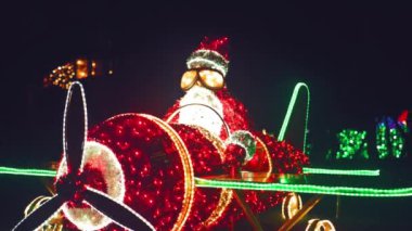 Noel Baba bir çelenk uçağında. Karanlıkta parlayan kırmızı Noel Baba. Noel ve Yeni Yıl 'ın sembolü. Noel Işığı Kurulumları. Karanlıkta parlayan figürler. 4k görüntü