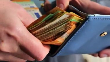 Cüzdanı para dolu, yakın plan. Avro banknotlarından oluşan büyük bir deste el cüzdana sokuluyor. Zenginlik kavramı. Yüksek kalite 4k görüntü