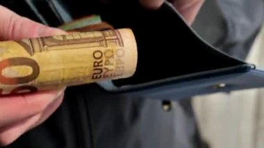 Para dolu cüzdan. Para transferinin yakın plan çekimi. Avro banknotları. Para cüzdana sığmaz. Avro banknotlarından oluşan büyük bir deste el cüzdana sokuluyor. Zenginlik kavramı. 4k görüntü