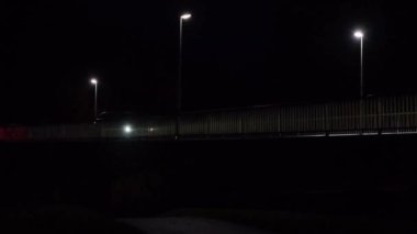 Araba karanlıkta ışıklarla köprüden geçiyor. Dedektif ve suç modu. Karanlık, gizemli bir atmosfer. Kara mizaç..