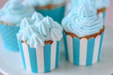 Çizgili mavi fincanlarda mavi kremalı kekler. Kremalı kek çeşitleri. Lezzetli porsiyonlu kek. Tatlı hamur işleri ve tatlılar pembe arka planda. Çikolata çeşitleri.. 