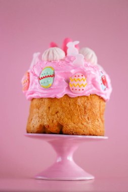 Pembe seramik tezgahta Paskalya pastası pembe kremalı ve pembe arka planda renkli süslemeler. Paskalya bayramı için fırın. Paskalya festivali pişirme. Paskalya yemeği. Festivalsel pişirme. 