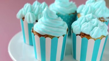 Çizgili mavi bardakta mavi kremalı kapkekler. Lezzetli porsiyonlu pastalar. Kremalı pasta çeşitleri. Tatlı hamur işleri ve tatlılar. 4k görüntü