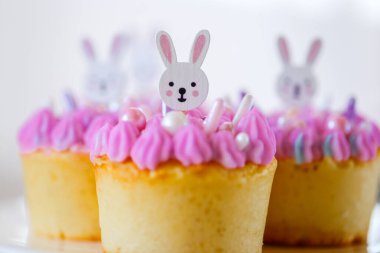Beyaz tavşanlı paskalya çörekleri pembe kremalı. Pembe şekerli şirin tavşan keki. Paskalya sofrası. Pastel tonlarında Paskalya pastası ve tatlılar. Bahar tatili için tatlı hamur işleri.. 