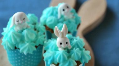 Mavi keten masa örtüsünde beyaz tavşanlı paskalya çörekleri. Yukarıdan manzara. Pastel mavisi tonlarda paskalya pastası pişirme ve tatlılar. Taze pişmiş yiyecekler. 4k görüntü