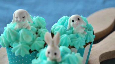 Paskalya sofrası. Beyaz tavşanlı beyaz tavşanlı kremalı paskalya çörekleri mavi keten masa örtüsü üzerinde tavşan şeklinde. Yukardan bak. Paskalya pastası pişirme ve pastel mavisi tonlarda şekerler. 
