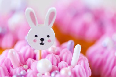 Pembe ve mor kremalı Paskalya Tavşanı Kekleri. Pembe kremalı beyaz tavşanlı Paskalya Kekleri. Katolik ve Ortodoks tatilleri. Bahar tatilleri için pişmiş yiyecekler. Pasta üzerine şirin tavşan süslemesi.