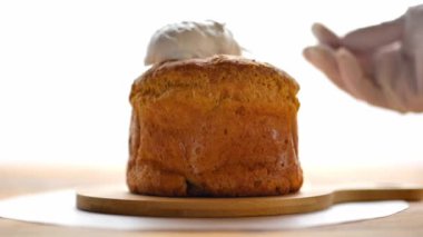 Paskalya pastası yapıyorum. Katolik ve Ortodoks bayram masaları. Beyaz eldivenli eller taze paskalya pastasına beyaz krema sürer. kremalı Paskalya keki. 4k görüntü