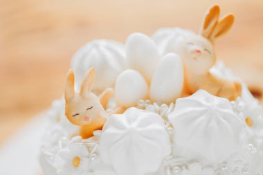 Paskalya pastaları. Ahşap bir masada açık renkli Paskalya dekoru. Bahar bayramı tatlıları. Katolik ve Ortodoks bayram masası. Pasta Üzerine Şirin Tavşan Dekorasyonu. 